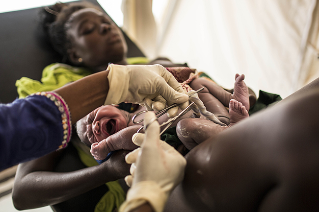 A midwife cuts the umbilical cord of a newborn baby in M’Poko camp, Central African Republic. Photo by Laurence Geai