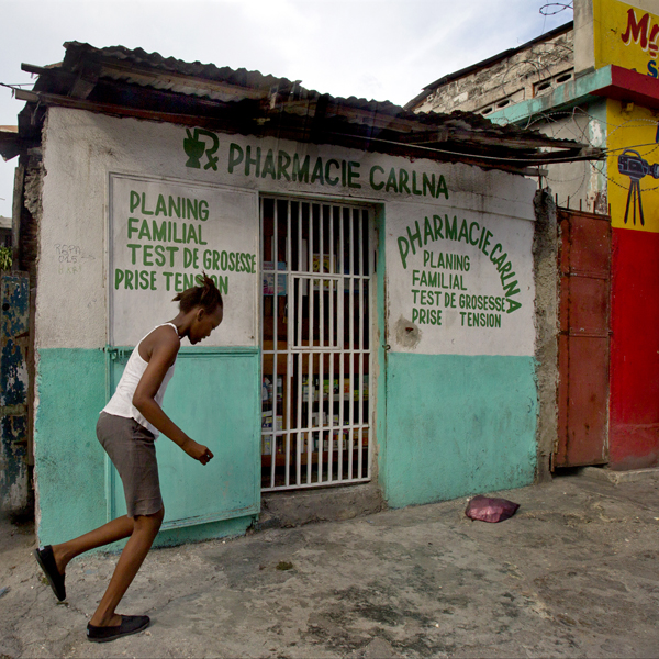In Haiti, a girl runs by a pharmacy that illegally sells drugs to induce abortion. Photo by Patrick Farrell